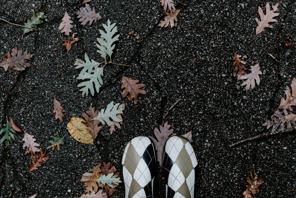 Image: woman's gum boots surrounded by autumn leaves