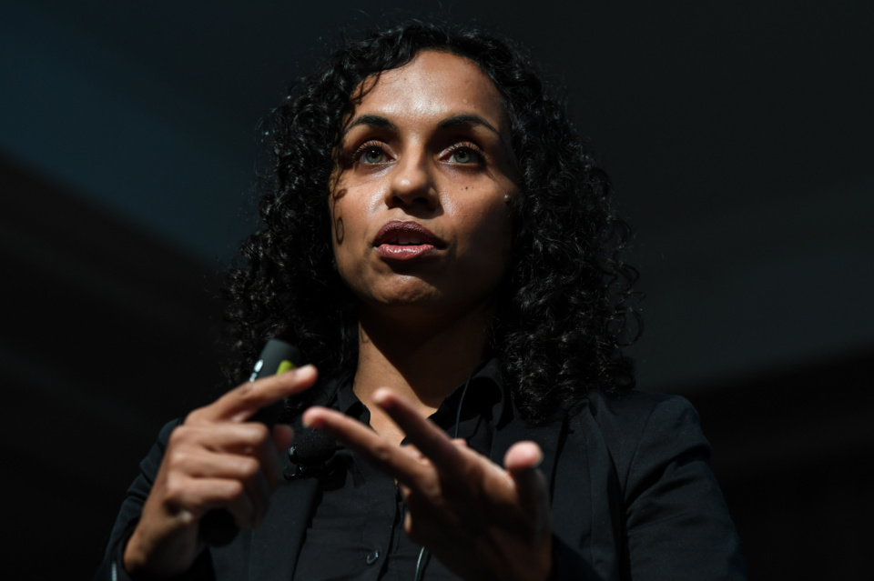 Image description: a photograph of Ramona speaking at an event. She is mid speech, and appears to be listing some key points.